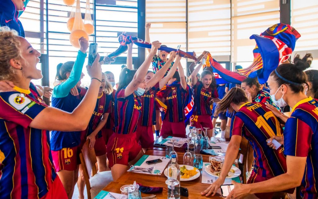 Jogadoras do Barcelona festejam título da Primeira Iberdrola ao redor de uma mesa com comes e bebes.